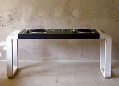 a table with two turntables on it in front of a concrete wall and cement floor