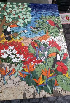 a painting on the ground with birds, flowers and plants painted on it's surface