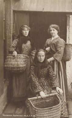 an old photo of three women standing next to each other with baskets in front of them