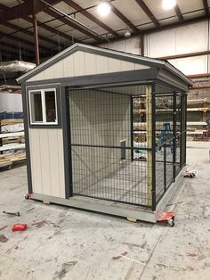 a dog kennel in the middle of a building with its doors open and windows closed