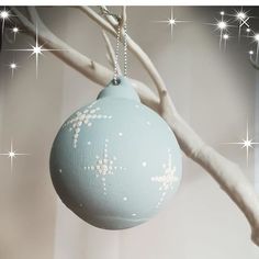 a blue ornament hanging from a tree with white stars on it's branches