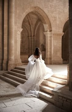 a woman in a white dress is walking up some stairs