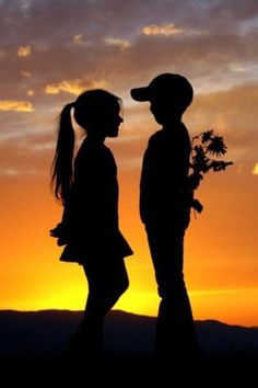 two people standing in front of a sunset