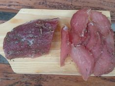 two pieces of meat sitting on top of a wooden cutting board