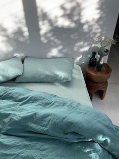 an unmade bed with blue sheets and pillows