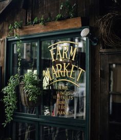 a store front with plants in the window and an advertisement on the door that says farm market