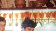 two young men standing next to each other in front of a shelf with baskets on it