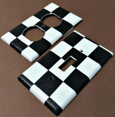 two black and white checkerboard switch plates on a brown surface with a hole in the middle