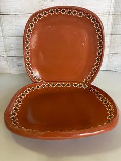 a brown bowl with black dots on the rim and bottom, sitting on a white surface