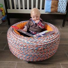 a baby sitting in a basket reading a book