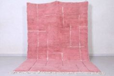 a pink rug with white lines on the top and bottom, in front of a wall