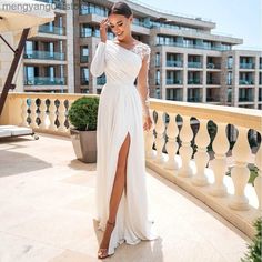 a woman in a white dress standing on a balcony