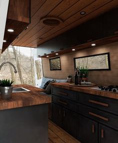 a kitchen with wooden floors and counter tops next to a window that looks out onto the woods