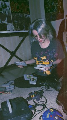 a woman sitting on the floor playing with some nintendo wii game console controllers and accessories