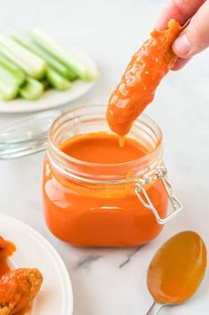 a person dipping something into a jar of sauce