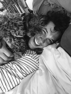 a man laying in bed next to a woman with curly hair and wearing a striped shirt