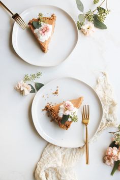 two white plates with slices of pie on them and flowers around the edges, along with gold forks