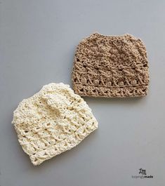 two crocheted hats sitting next to each other on top of a gray surface