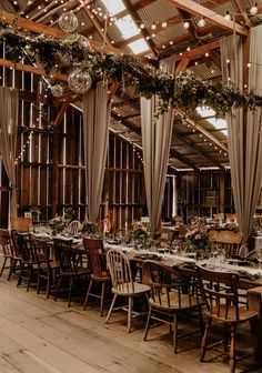 an indoor dining area with wooden tables and chairs, decorated with greenery and hanging chandeliers