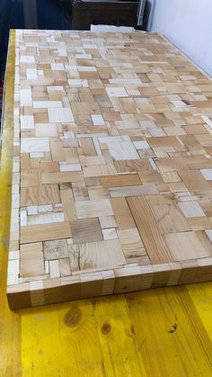 a large wooden cutting board sitting on top of a yellow tablecloth covered flooring