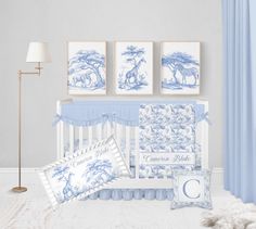 a baby's room with blue and white wall art, crib bedding, lamp, and pictures on the wall