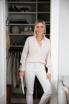 a woman standing in front of a closet with white pants and shoes on the floor