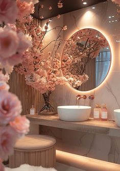 there are two sinks in the bathroom with flowers on the counter and a round mirror above them