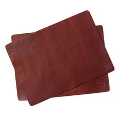 two brown leather placemats sitting on top of each other