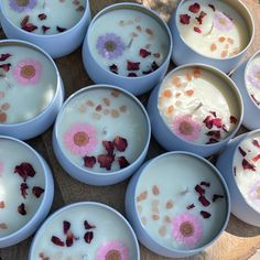 many bowls filled with different types of flowers on top of a wooden table next to each other