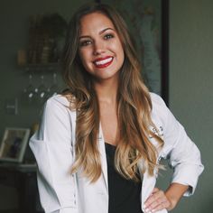 a woman standing with her hands on her hips wearing a white blazer and black top