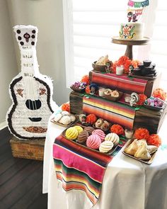 a table topped with lots of food next to a guitar shaped cake and cupcakes