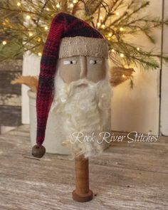 an old fashioned santa claus head on top of a wooden pole next to a christmas tree