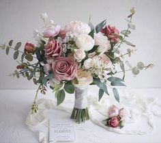 a bouquet of flowers sitting on top of a white table cloth next to a sign