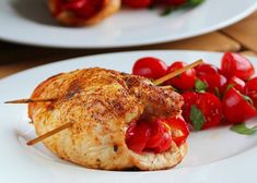 two white plates with food on them, one has meat and the other has tomatoes