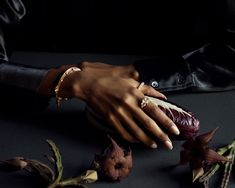 a woman's hand holding a piece of food in her left hand and flowers on the table