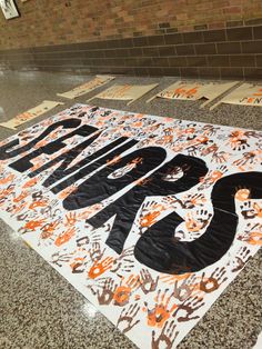 an orange and black sign on the ground in front of a brick wall with writing