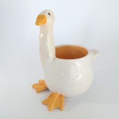 a white duck shaped vase with an orange beak