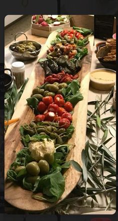 a long wooden platter filled with lots of different types of food on top of a table