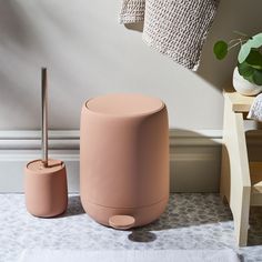 a pink stool next to a white towel and potted plant