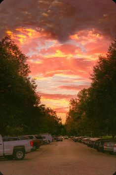 a parking lot filled with lots of parked cars under a colorful sky at sunset or sunrise