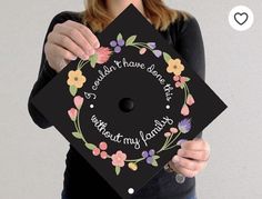 a woman holding up a graduation cap with flowers on it