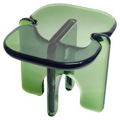 a glass table with two black legs and a green seat that has been turned upside down