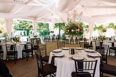 tables and chairs are set up in a tented area with white tablecloths