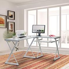 a computer desk with a monitor and keyboard on it in front of a large window