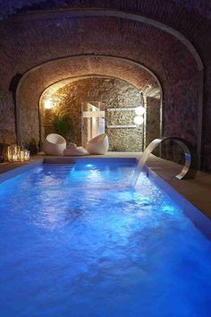 an indoor swimming pool with blue lights and water running from it's sides to the floor