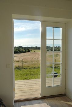 an empty room with sliding glass doors leading to a grassy field outside the door is open