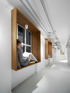 a woman sitting on a window sill reading a book