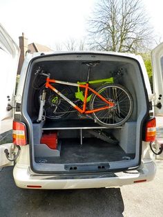 an orange bike is in the back of a white van with it's cargo door open