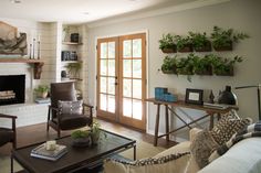 a living room filled with lots of furniture and plants on the wall above the fireplace