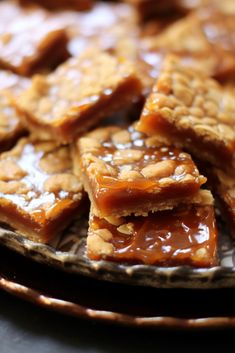 several pieces of dessert on a plate with caramel sauce and almonds in the background